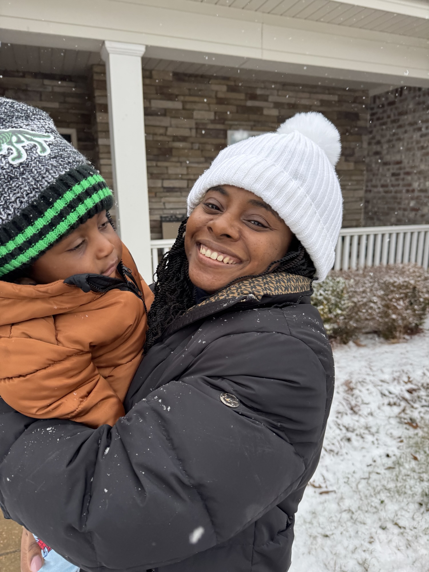 Ivy Sweeney Ross smiling and holding her young son outside in the snow, representing the beauty and depth of winter seasons in life.